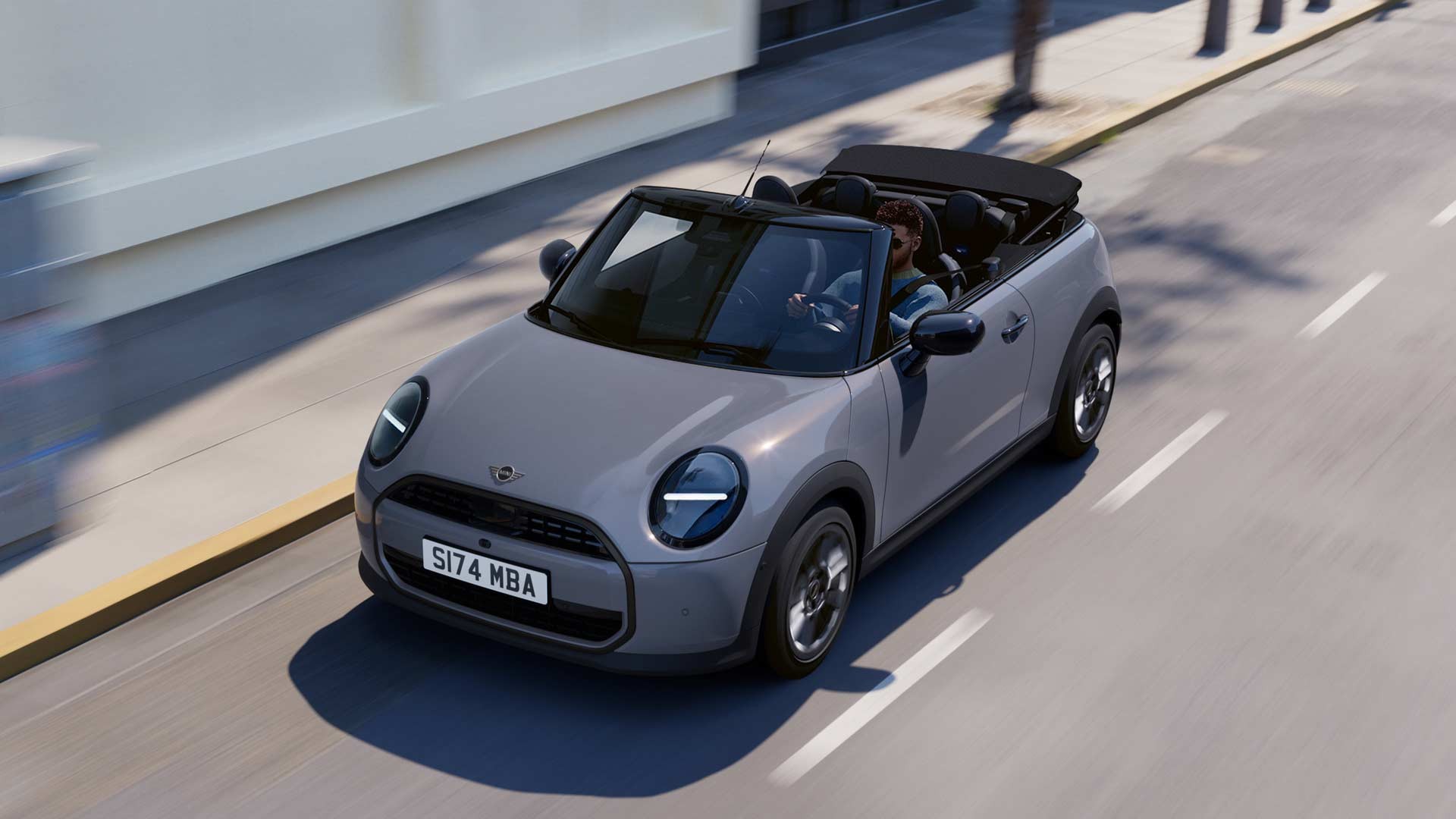 The new MINI convertible is cruising along a road, highlighting its stylish features and open-top design.